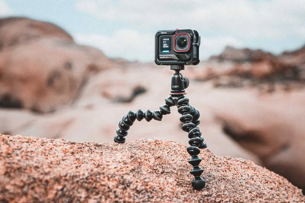 Action camera mounted on a JOBY GorillaPod flexible tripod with its legs spread across an uneven rock surface.
